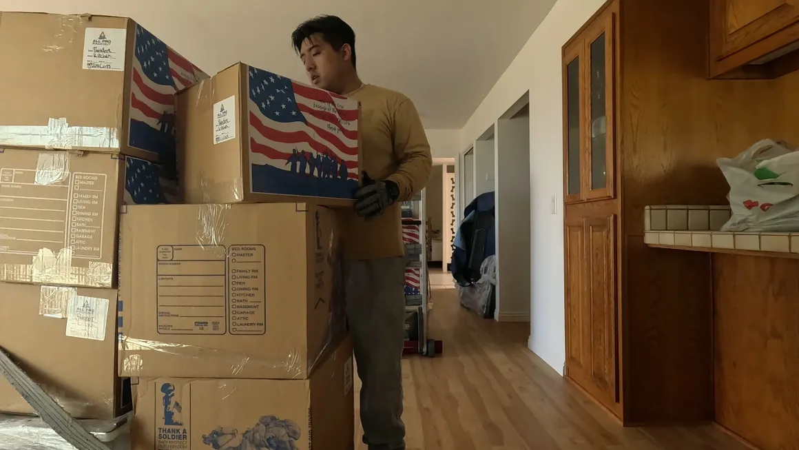 Han's Moving mover carrying labeled moving boxes through a home