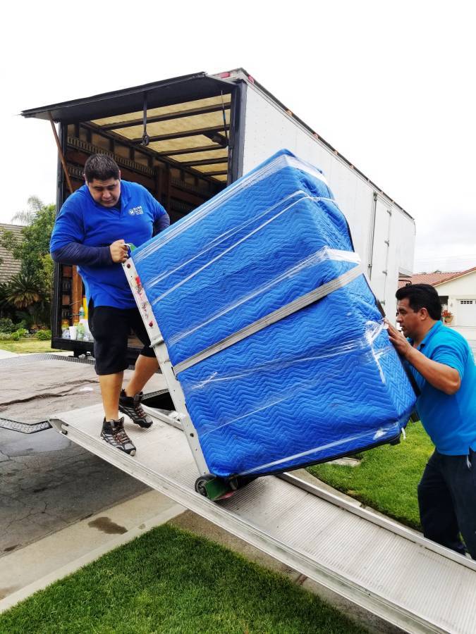 Han's Moving team loading a wrapped sofa up the truck ramp